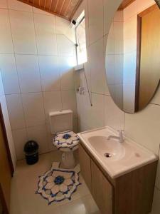 a bathroom with a sink and a toilet and a mirror at Casa em Condominio próximo trevo Cataratas em Cascavel in Cascavel