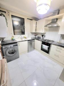 een keuken met witte kasten en een wasmachine en wastafel bij Three Bed Flat In Mile End in Londen