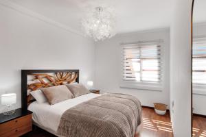 コラレホにあるVilla Corralejoの白いベッドルーム(ベッド1台、シャンデリア付)