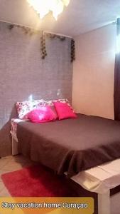 um quarto com uma cama com almofadas cor-de-rosa em stay vacation home curaçao em Willemstad