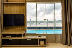 Duplex pé na areia com vista deslumbrante RAT001 في بورتو بيلو: غرفة معيشة فيها تلفزيون ونافذة كبيرة