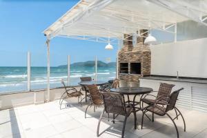 a patio with a table and chairs and the ocean at Duplex pé na areia com vista deslumbrante RAT001 in Porto Belo