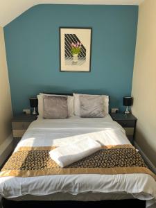 una camera con un letto con una parete blu di The Harp Freehouse and Guesthouse a Ipswich