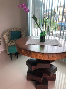 een houten tafel met een vaas met een bloem erop bij A casa da Keila - Balneário Camboriú in Balneário Camboriú