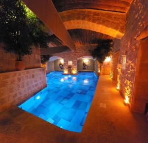 an indoor swimming pool with blue lighting in a building at Fresco Cave Suites Cappadocia in Ürgüp