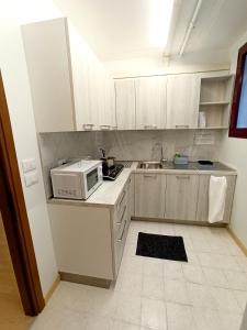 una pequeña cocina con armarios blancos y microondas en IL LOFT AI PILA, en Montebelluna