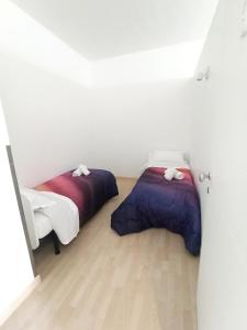 Habitación con 2 camas, paredes blancas y suelo de madera. en IL LOFT AI PILA, en Montebelluna