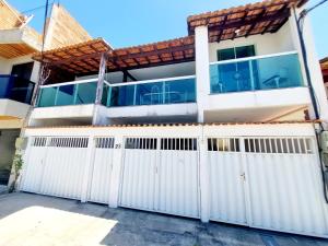 une maison blanche avec une clôture blanche dans l'établissement Kitnet Quarto Sala Cozinha com Ar Condicionado 102, à Cabo Frio