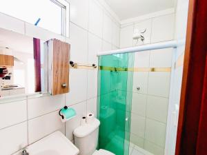 La salle de bains est pourvue de toilettes et d'une douche en verre. dans l'établissement Kitnet Quarto Sala Cozinha com Ar Condicionado 102, à Cabo Frio