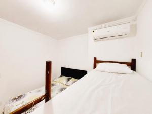 - une chambre blanche avec un lit et un plafond dans l'établissement Kitnet Quarto Sala Cozinha com Ar Condicionado 102, à Cabo Frio