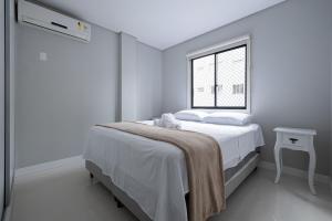 - une chambre blanche avec un lit et une fenêtre dans l'établissement Apto aconchegante a 450m do mar EAN503, à Balneário Camboriú