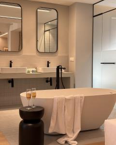 a bathroom with a tub and two glasses of wine at AIONION RESIDENCES by K&K in Athens