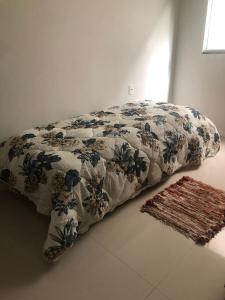 ein Bett mit einer Decke und einem Teppich in einem Zimmer in der Unterkunft A casa da Keila - Balneário Camboriú in Balneário Camboriú
