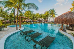 a resort swimming pool with chairs and palm trees at Privê Pontal de Maracaipe in Porto De Galinhas