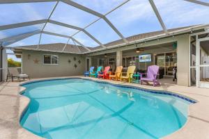 - une piscine avec des chaises et une maison dans l'établissement Lush Privacy, Large Outdoor Living Space, Heated Pool,& Pet-friendly - Villa Veronica- Roelens, à Cape Coral