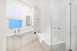 ein weißes Bad mit einer Badewanne, einem Waschbecken und einer Dusche in der Unterkunft London Choice Apartments - Baker Street- Regent's Park in London