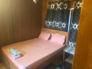 1 cama pequeña con 2 almohadas rosas en una habitación en La fierté, en Ziguinchor