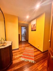 um quarto com paredes amarelas e um tapete num piso de madeira em Apartamento en la costa em Lekeitio