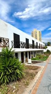 a white building with black shuttered windows on it at Las Americas Bungamar apartment in Playa de las Americas