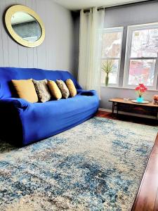 eine blaue Couch in einem Wohnzimmer mit einem Teppich in der Unterkunft Merj's Guest House in Wolesly in Winnipeg