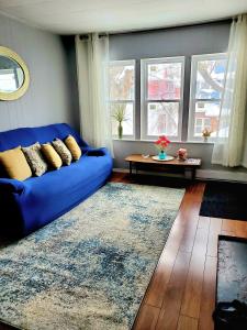 Sofá azul en la sala de estar con ventanas en Merj's Guest House in Wolesly, en Winnipeg