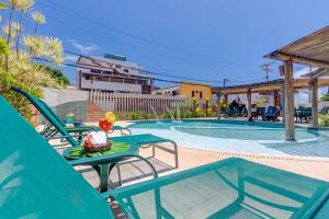 a pool with two chairs and a table with a drink on it at Pousada Praia Bela in Ilhéus