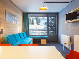 a living room with a blue couch and a window at Studio Les Arcs 1800, 1 pièce, 5 personnes - FR-1-346-357 in Arc 1800