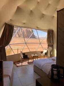 a room with two beds and a large window at Diamond Wadi Rum Luxury Camp in Wadi Rum