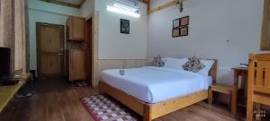 1 dormitorio con 1 cama blanca y TV en Tirthan Grand Riverside en Banjār