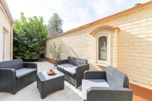 un patio con sillas, una mesa y una pared de ladrillo en Villa Spacieuse 6 ch/12 personnes/ 6 SDB WC privée en Valenciennes