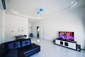 a living room with a black couch and a flat screen tv at The Guestvilla644 in Hua Hin