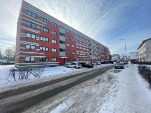 een rood gebouw op een besneeuwde straat met geparkeerde auto's bij Rohuaia 22 Apartment in Rakvere