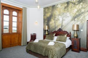 a bedroom with a bed with a painting on the wall at Watermouth Castle, West Tower Apartment in Ilfracombe