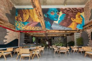una stanza con tavoli e sedie e un murale di Hotel Poblado Park a Medellín