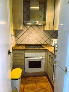 - une petite cuisine avec cuisinière et tabouret jaune dans l'établissement Apartamento Balcón a Pistas, à Sierra Nevada