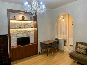 ein Wohnzimmer mit einem Tisch, einem TV und einem Kronleuchter in der Unterkunft Best Location Renovated Home in Tbilisi City