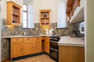 a kitchen with wooden cabinets and a stove at Watermouth Castle, Harbour Apartment in Ilfracombe