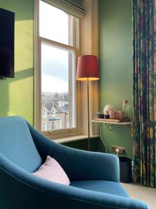 a living room with a blue couch and a window at Fellpack House in Keswick