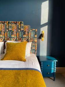 a bed with a colorful headboard and a blue table at Fellpack House in Keswick