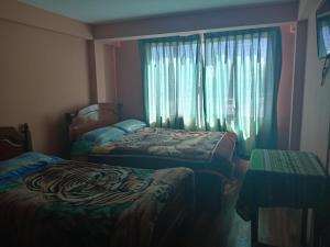 1 Schlafzimmer mit 2 Betten und einem Fenster mit Vorhängen in der Unterkunft Manco Kapac in Copacabana