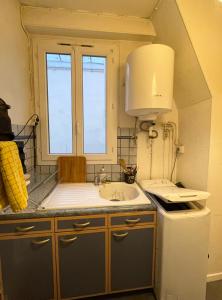 a kitchen with a sink and a stove and a window at Studio parisien in Paris