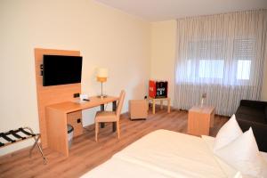 ein Wohnzimmer mit einem Schreibtisch und einem Bett in der Unterkunft Hotel Paffhausen in Wirges