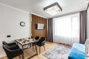 a living room with a table and chairs at Alpine serenity deLuxe apartment with MOUNTAIN views near the ADK shopping center and Sairan METRO station in Almaty