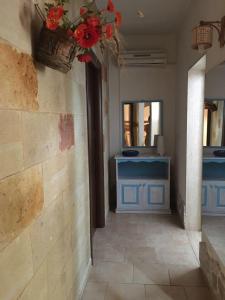 a hallway with a bathroom with blue cabinets and flowers at Tenuta Nonno Carmine in Porto Cesareo
