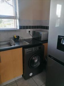 a kitchen with a washing machine and a microwave at Peaceful Home with Sbo in Pietermaritzburg