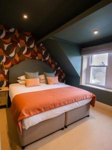 a bedroom with a large bed with an orange comforter at Fellpack House in Keswick