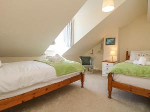 two beds in a attic bedroom with a window at Sea Star in Porthleven