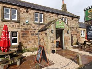 an old stone building with a sign in front of it at Jasmine Cottage in Alnwick