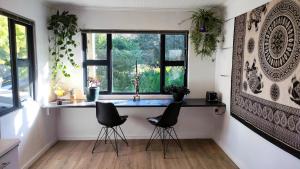 a kitchen with two chairs and a counter with a window at Blissful Country Garden King Bed Cottage in Grabouw