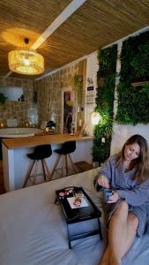 une femme assise sur un lit avec un plateau dans l'établissement Les Spas de la mer, Suite & Spa, Love room, Plein Cœur du Grau, au Grau-du-Roi